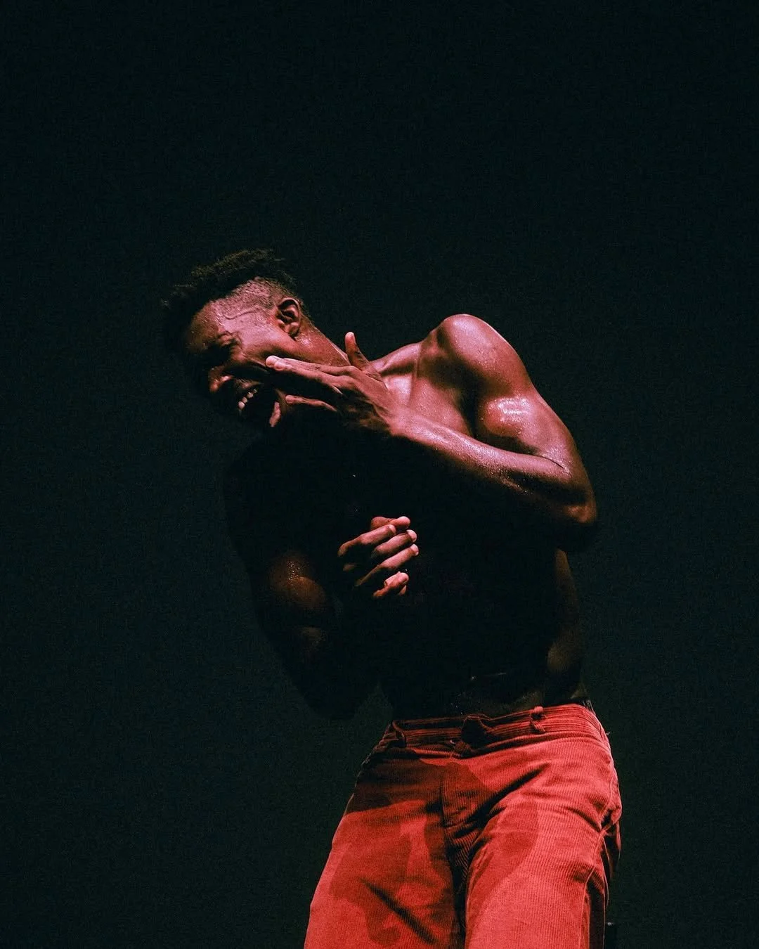 Oulouy in red pants against a black background.