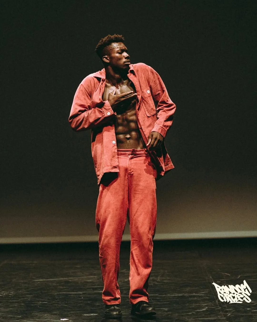 Oulouy in a red jacket performing on stage.